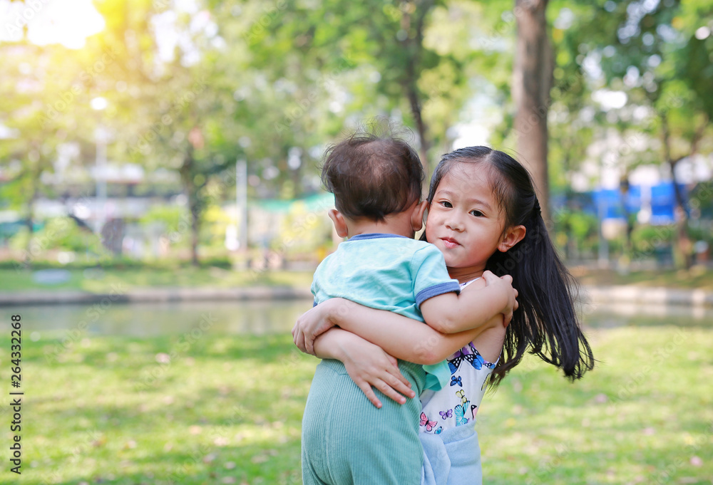 Asian sister carrying her little brother in the garden outdoor. Asian sister carrying her little brother in the garden outdoor.