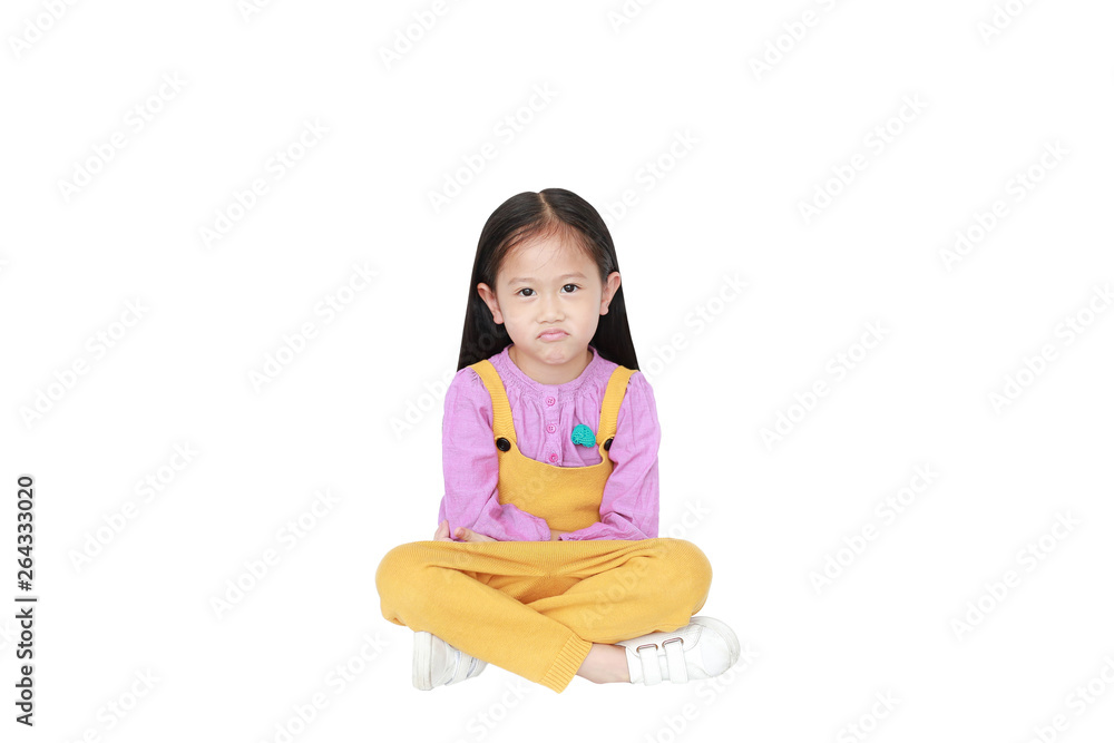 Portrait of angry little Asian child girl in pink-yellow pink-yellow dungarees sitting isolated on white background with copy space. Portrait of angry little Asian child girl in pink-yellow pink-yellow dungarees sitting isolated on white background with copy space.