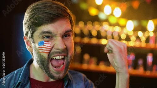 Extremely happy american soccer fan with flag on cheek making yes gesture, win photo