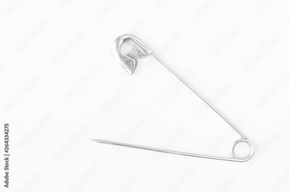Safety pin close up on white background. Macro photography, flat lay, minimalism. Top view, copy space. Safety pin close up on white background. Macro photography, flat lay, minimalism. Top view, copy space.