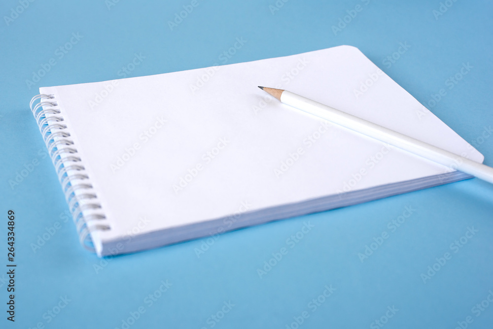 A pencil and a notebook on blue surface. Close up. Copy space for text A pencil and a notebook on blue surface. Close up. Copy space for text