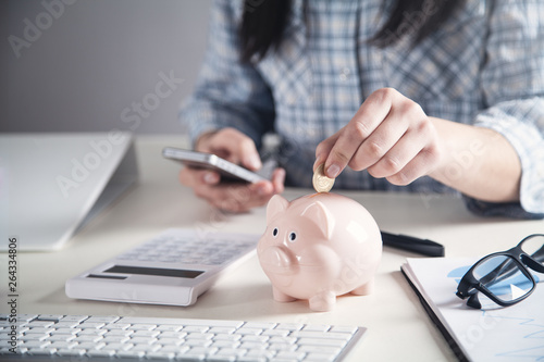 Business girl putting coin in a piggy bank. Saving money