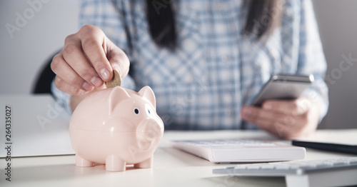 Business girl putting coin in a piggy bank. Saving money