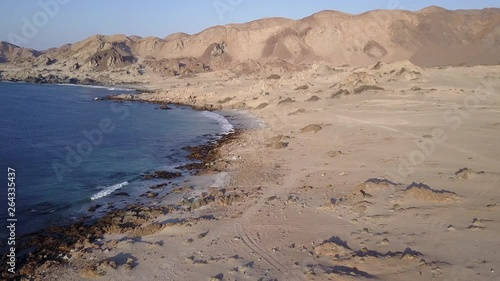 Las Tortolas beach aerial footage at Atacama Desert the sunset ray lights illuminate this amazing and idyllic beach in the middle of the desert, an arid awe landscape crashed by Pacific Ocean waters