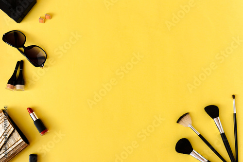 Professional decorative cosmetics and makeup brushes on yellow background. Beauty fashion concept.