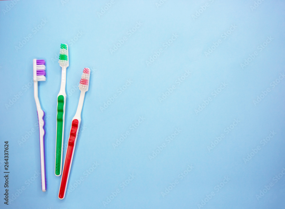 Multi-colored toothbrushes on a blue background with copy space. Flat lay. Top view. Multi-colored toothbrushes on a blue background with copy space. Flat lay. Top view.