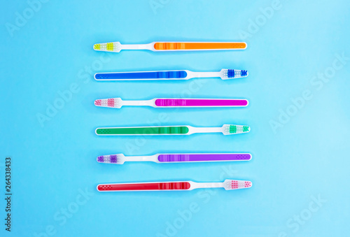 Multi-colored toothbrushes on a blue background. Flat lay. Top view.