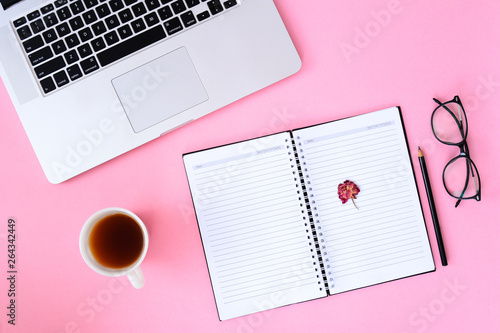 Office desk table with notebook,smartphone and coffee cup laptop. pink background flat lay top view