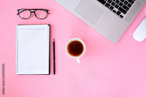 Office desk table with notebook smartphone and coffee cup laptop. pink background flat lay top view