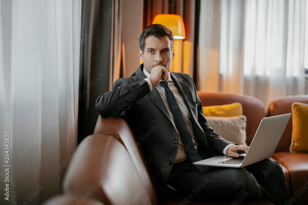 Man working on his laptop at the hotel. Executive manager typing on his laptop. Businessman sitting on the sofa working. Man working on his laptop at the hotel. Executive manager typing on his laptop. Businessman sitting on the sofa working.