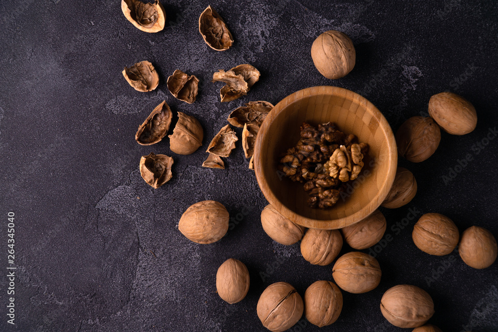 Cracked walnuts in wooden bowl and on black slate surface. Healthy nuts and seeds composition. Cracked walnuts in wooden bowl and on black slate surface. Healthy nuts and seeds composition.