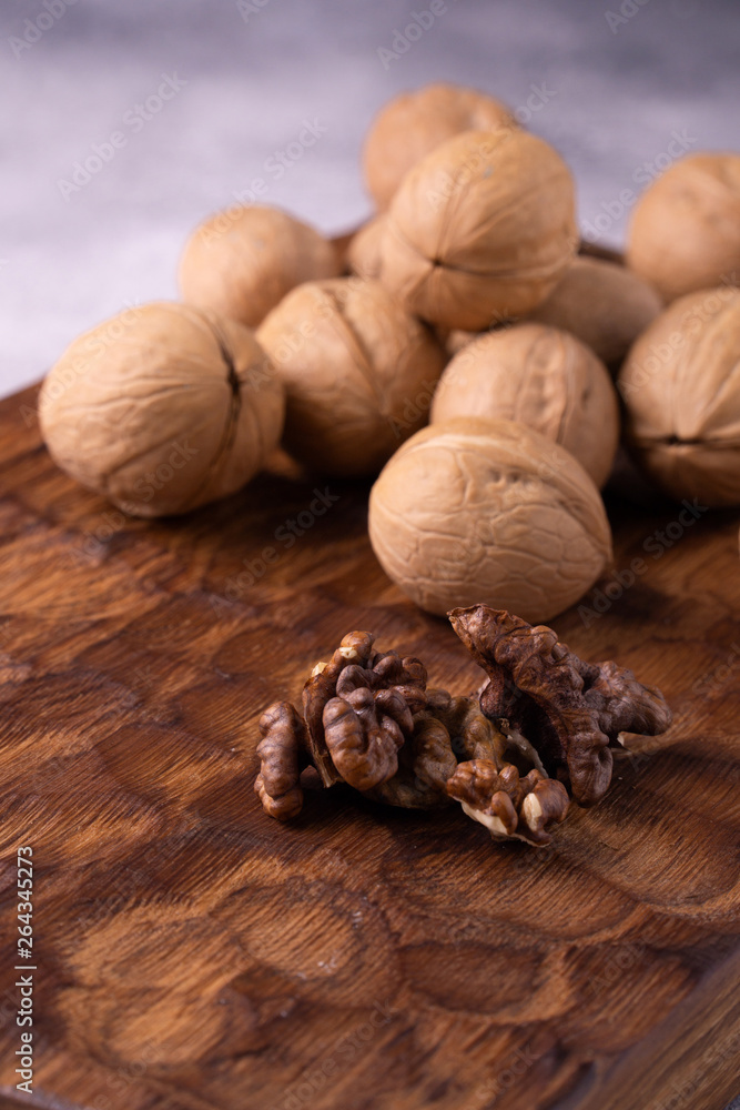 Bunch of walnuts on carved wooden board, bright background. Healthy nuts and seeds composition, background. Bunch of walnuts on carved wooden board, bright background. Healthy nuts and seeds composition, background.