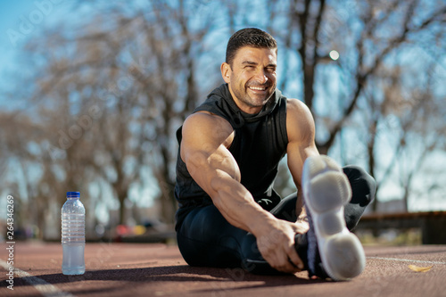 Fototapeta Naklejka Na Ścianę i Meble -  Athlete stretches. Man stretching before a workout. Guy trains outdoors, warms up before training.