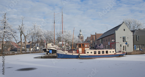 Meppel wintertime snow ice Netherlands. Boat in frozen canal. Netherlands. Barge. Churchtower. Stoombootkade. © A