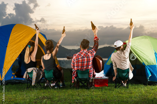 A group of Asian men and women are camping near a reservoir to relax and party.