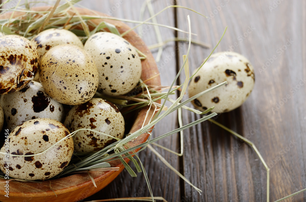 Fresh organic quail eggs in wooden bowl on rustic kitchen table. Space for text Fresh organic quail eggs in wooden bowl on rustic kitchen table. Space for text
