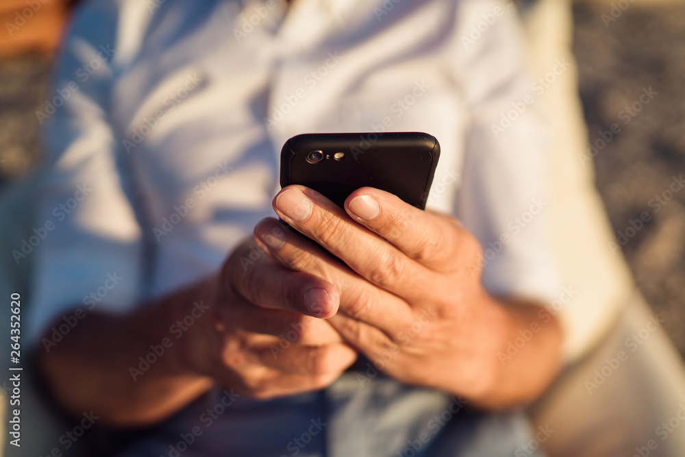 Senior man using smartphone during sunset. Close up Senior man using smartphone during sunset. Close up