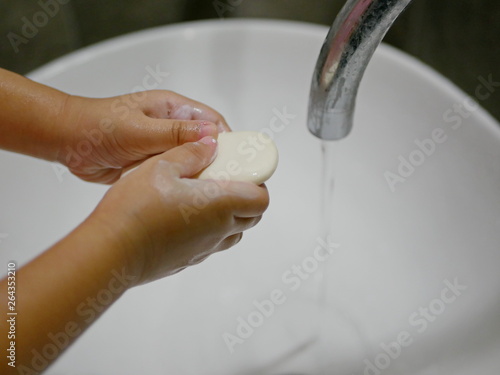 Close up of a little baby girl's hands with a soap learning to wash hands by herself - child development by allowing them to do things by themselves photo