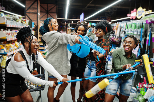 Group of five african womans with dust mop  toilet brush and bucket having fun in household cleaning items department in supermarket.