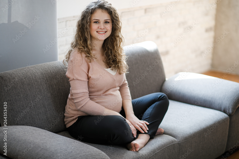 Beautiful pregnant woman sits and touches belly with hands, pregnancy concept