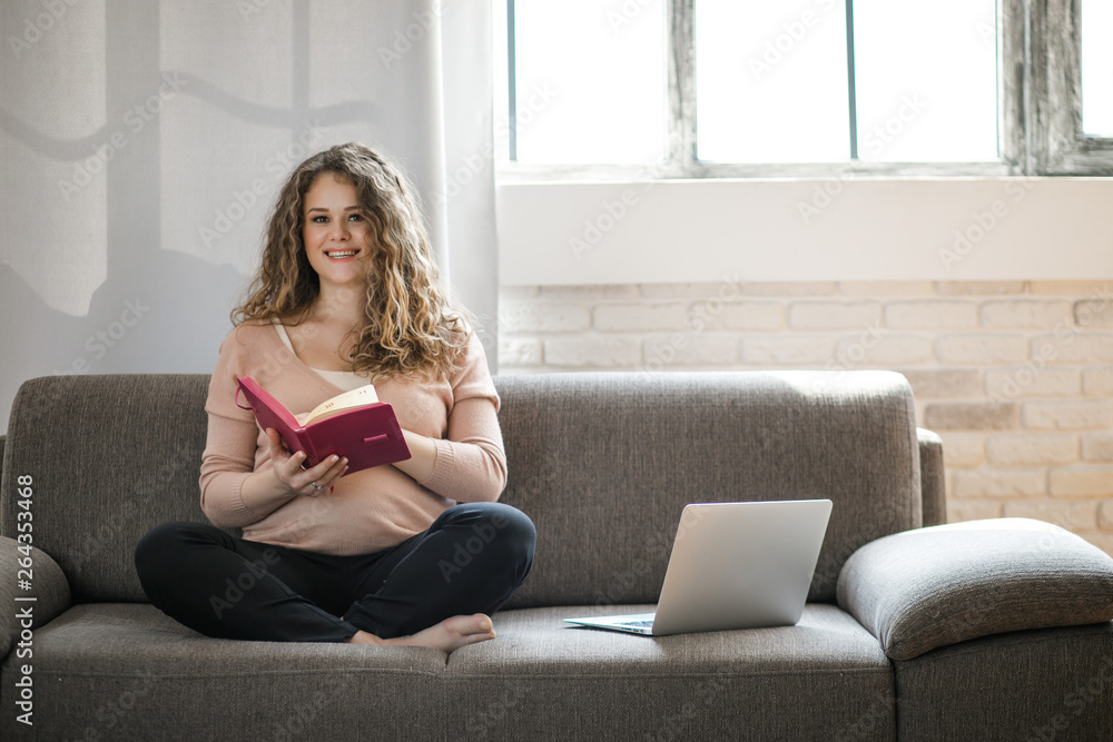A pregnant woman working on a laptop. Pregnant typing something on laptop while sitting at her workplace in office. A pregnant woman working on a laptop. Pregnant typing something on laptop while sitting at her workplace in office.