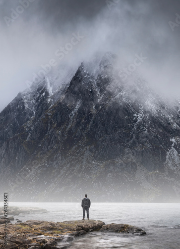 Fototapeta Man stood in front of foggy misty mountain to give scale of mountain size and co