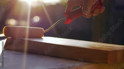 Professional carpenter applying a clear layer of varnish to a smooth wood 