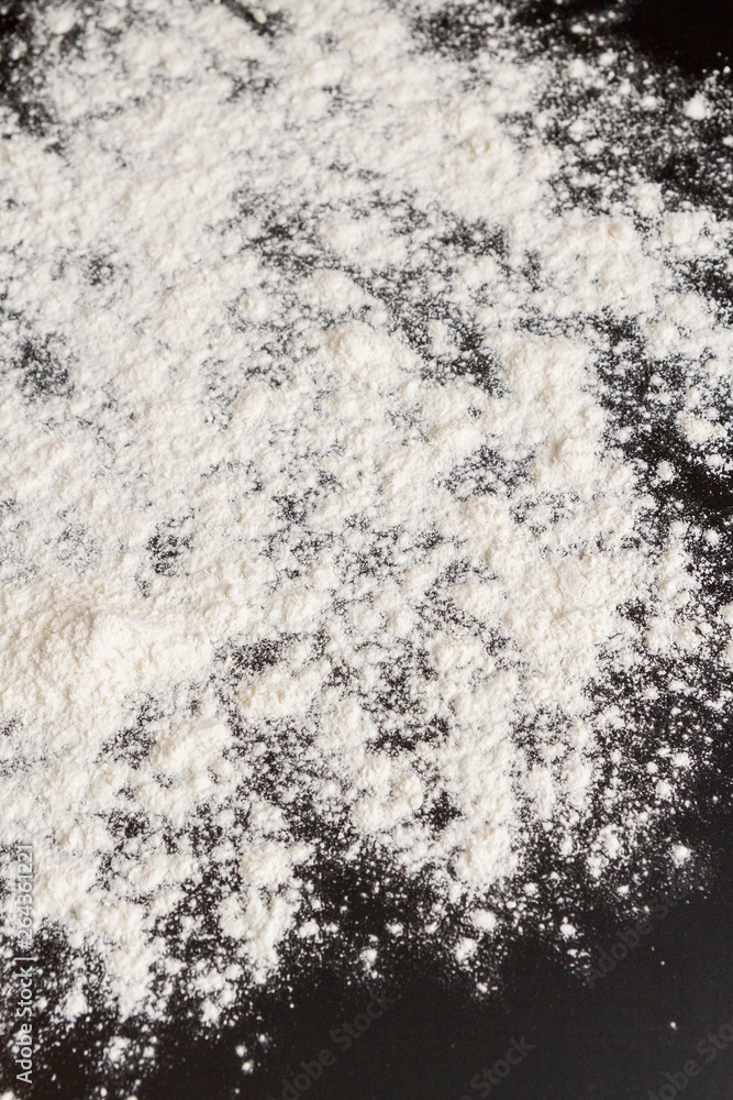 White flour is poured on a black table before cooking cookies White flour is poured on a black table before cooking cookies
