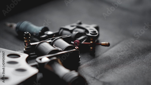 Tattoo machine and tattoo supplies on dark background - for banners