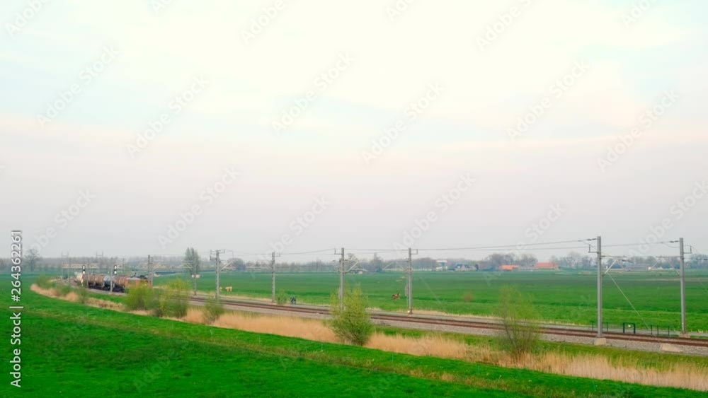 Freight train passing in the evening on an elevated railroad track on the Hanzelijn in the countryside seen from an overhead bridge. Freight train passing in the evening on an elevated railroad track on the Hanzelijn in the countryside seen from an overhead bridge.