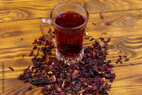 Glass cup of red hibiscus tea (carcade, roselle) on wooden table © olyasolodenko
