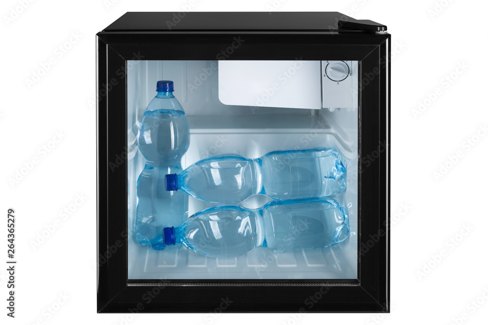 in a small black refrigerator with a glass door there are three plastic bottles of water, concept cooling, on a white background in a small black refrigerator with a glass door there are three plastic bottles of water, concept cooling, on a white background