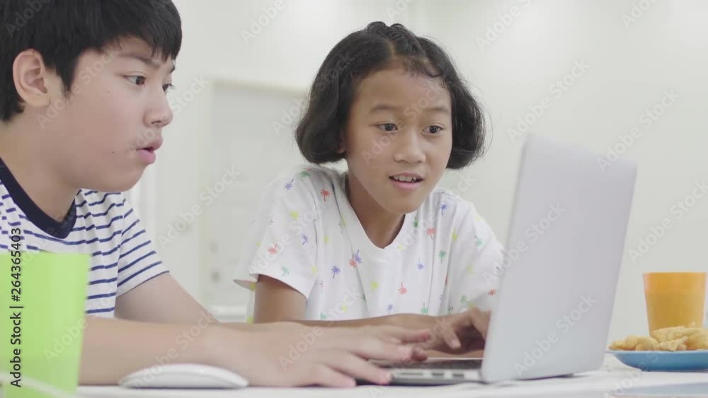 Young asian boy and girl playing with laptop computer at home. Children are playing online game on a laptop computer together. Dolly shoot 60fps. Young asian boy and girl playing with laptop computer at home. Children are playing online game on a laptop computer together. Dolly shoot 60fps.