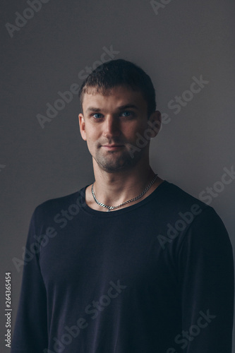 handsome man shows off gray clothes on grey background
