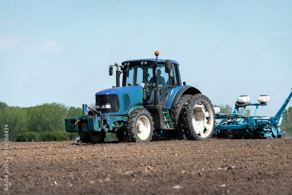 a large blue tractor prepares the land for planting a large blue tractor prepares the land for planting