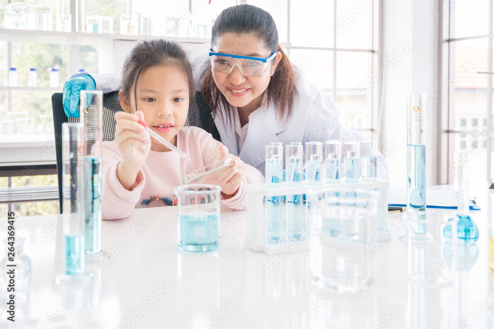 Asian girl school student performing experiment in chemistry lab with scientist teacher Asian girl school student performing experiment in chemistry lab with scientist teacher