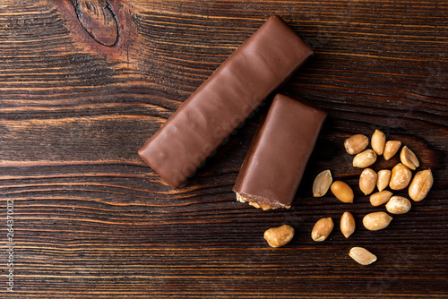 Chocolate bar with caramel and peanut on dark wooden background.  photo