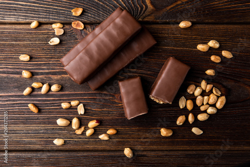 Photos Chocolate bar with caramel and peanut on dark wooden background.