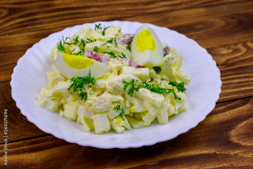 Salad with chinese cabbage, onion, sausage, eggs and mayonnaise on wooden table Salad with chinese cabbage, onion, sausage, eggs and mayonnaise on wooden table