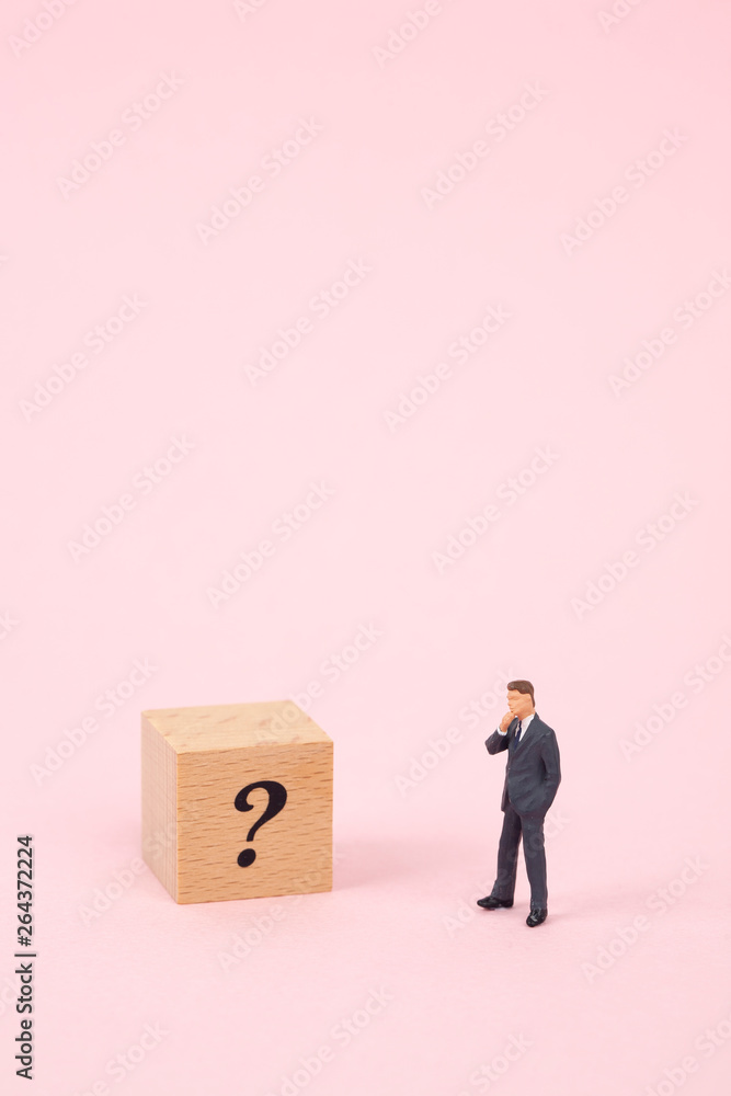 miniature businessman with question mark on wood cube miniature businessman with question mark on wood cube
