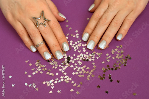 stylish silver color female manicure on purple backg