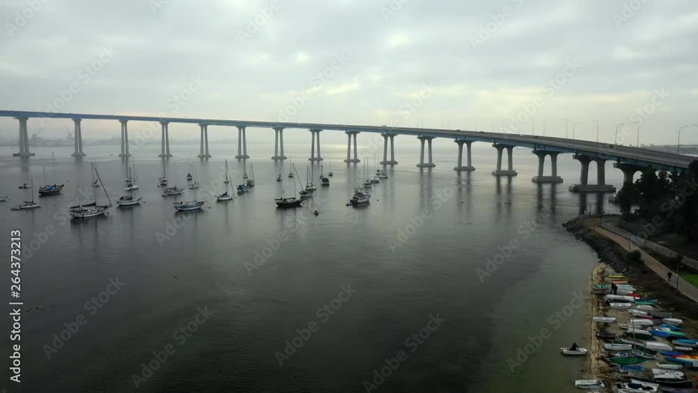 Aerial Descend: Boats Floating In Ocean Water Under Bridge On Cloudy Day in San Diego, United States of America Aerial Descend: Boats Floating In Ocean Water Under Bridge On Cloudy Day in San Diego, United States of America