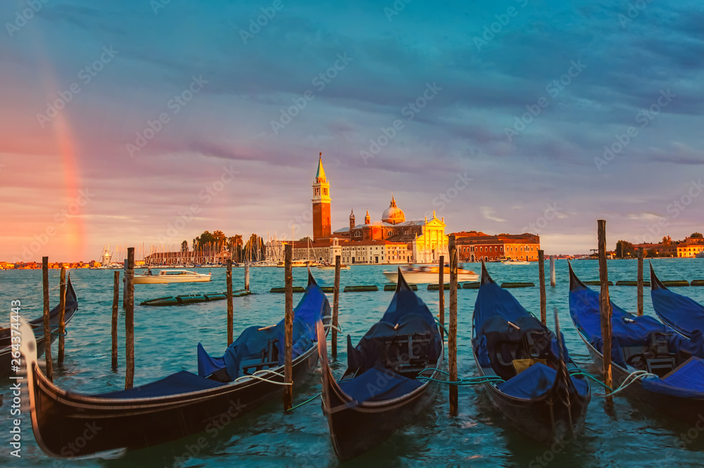 Colorful landscape with sunset sky, rainbow and gondolas parked near piazza San Marco in Venice. Church of San Giorgio Maggiore in the background, Italy. Europe tourism concept.