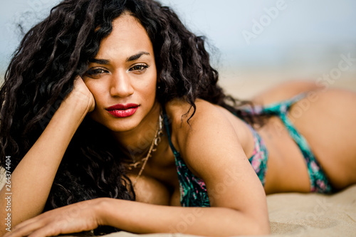 portrait of beautiful girl in black posing in the sand of the beach