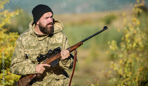 Bearded hunter spend leisure hunting. Focus and concentration of experienced hunter. Regulation of hunting. Hunting masculine hobby concept. Man brutal gamekeeper nature background. Hunter hold rifle