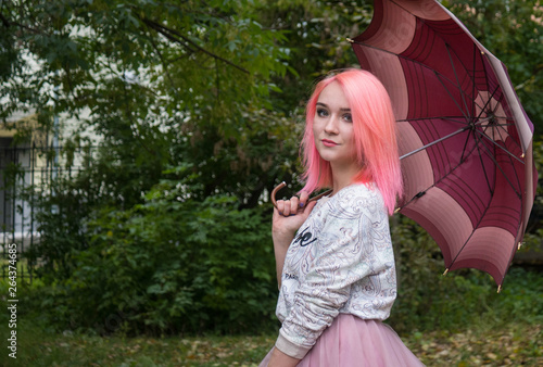 girl woman with pink hair and a pink skirt holding an umbrella. turned on the camera. horizontally