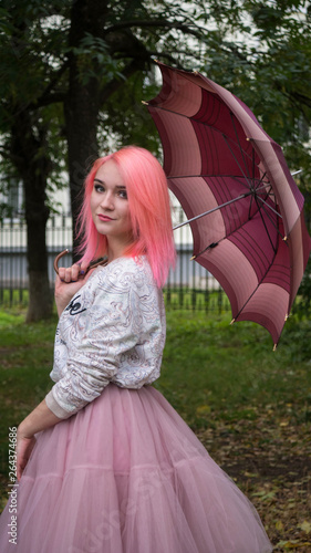 girl woman with pink hair and a pink skirt holding an umbrella. turned on the camera. vertical