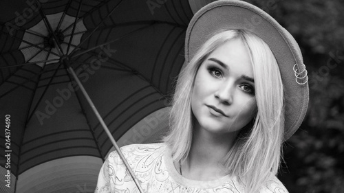 portrait of beautiful blonde girl in hat with umbrella. close-up, looking at the camera. black and white photo  horizontally