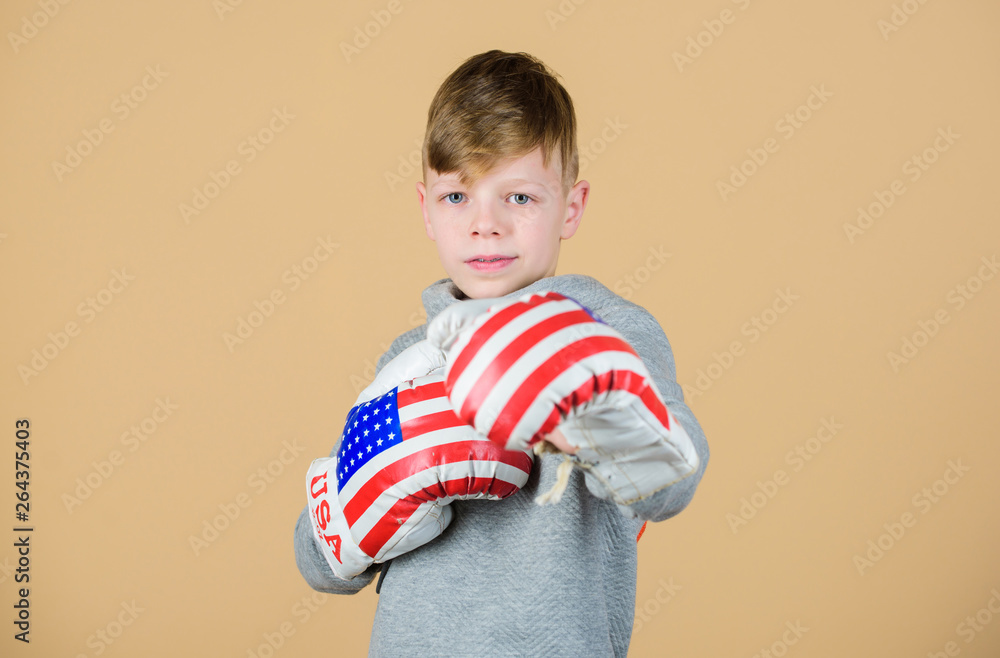 punching knockout. Childhood activity. workout of small boy boxer. Sport success. Confident in his fitness regime. energy health. usa independence day. Happy child sportsman in boxing gloves punching knockout. Childhood activity. workout of small boy boxer. Sport success. Confident in his fitness regime. energy health. usa independence day. Happy child sportsman in boxing gloves