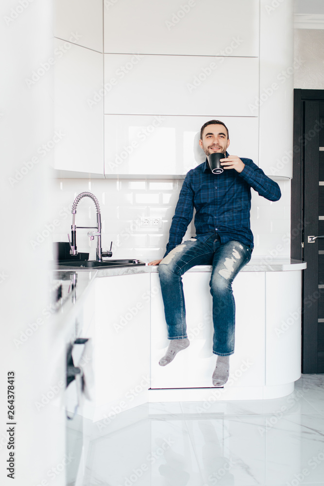 Portrait of happy young man having coffee in kitchen Portrait of happy young man having coffee in kitchen
